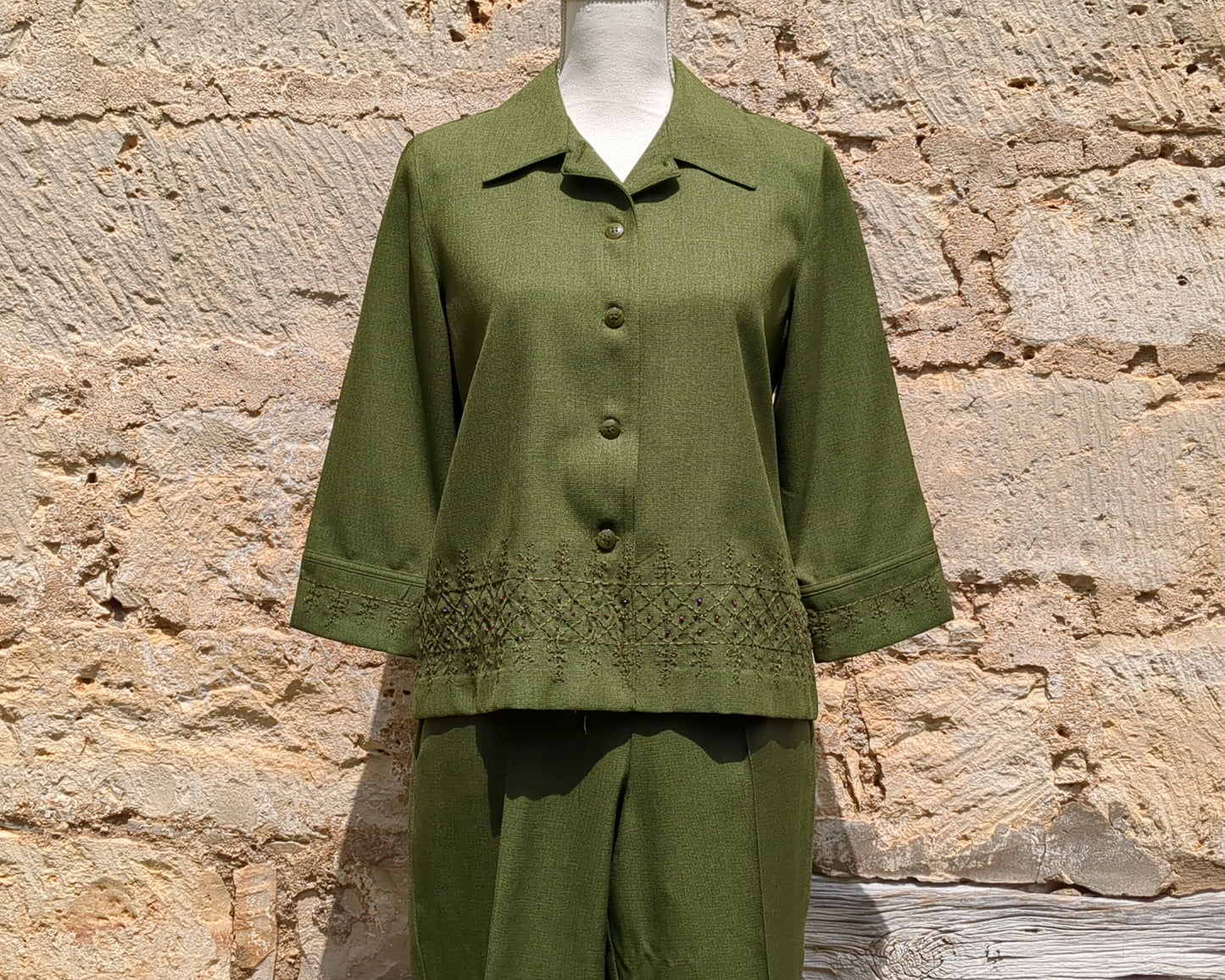 Green outfit on a mannequin against a stone wall background