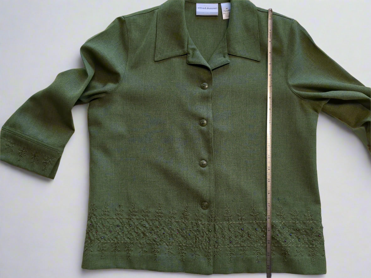 Green blouse with lace details on a white surface