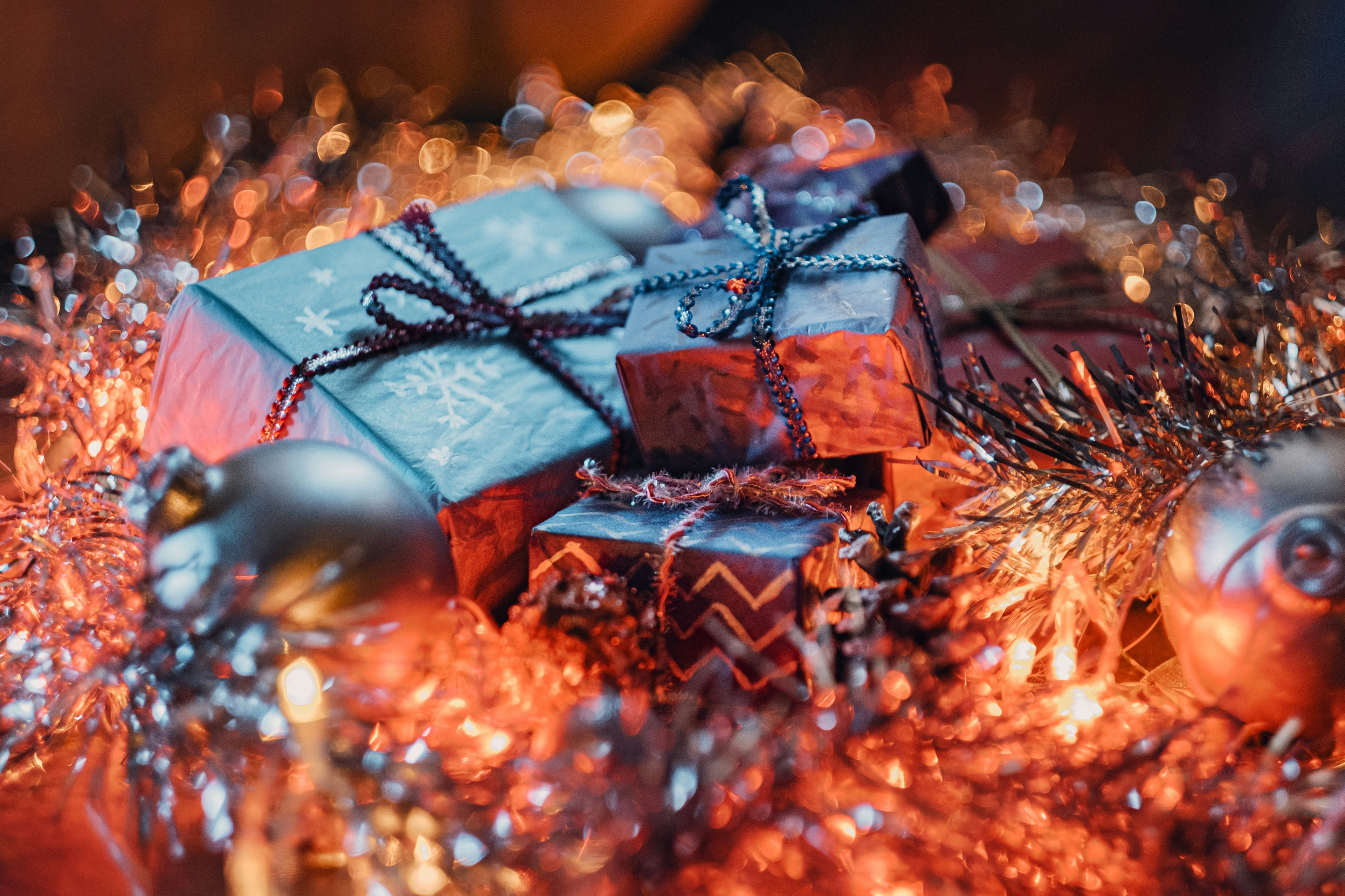 Photo by Yevhen Buzuk on Unsplash. Christmas gifts nestled in tinsel, warm lights, and ornaments
